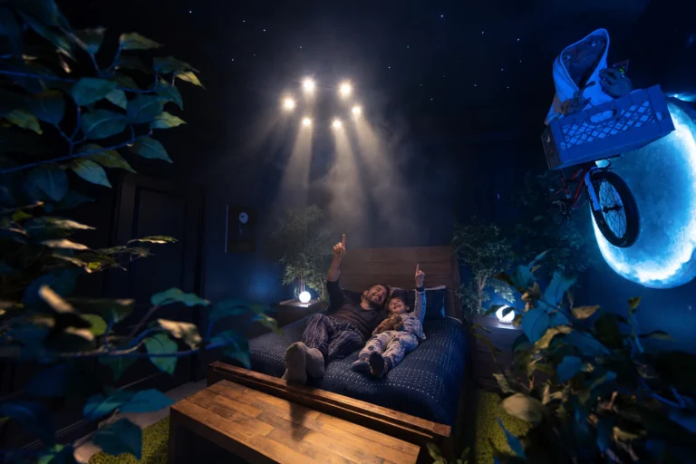 A dad and son lie in bed under starlight beams in The Extra-TerRestful Suite, the forest-and-moon bedroom at Electronic Ice Castle
