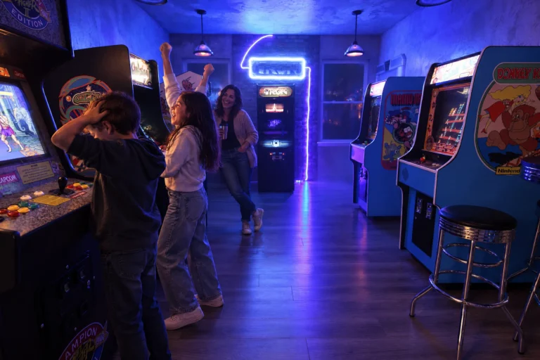 A sister throws her arms up after beating her brother at an arcade game in Flynn's Arcade at Electronic Ice Castle