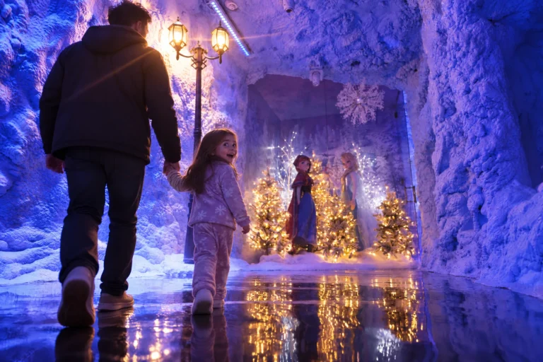 A dad and daughter take their first walk down the glowing ice corridor toward the Ice Princess Suite at Electronic Ice Castle