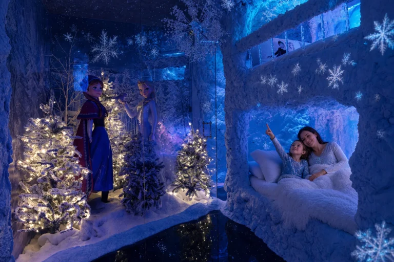 A mom and daughter cuddle in a snowy bunk nook watching the snowflake lights in the Ice Princess Suite at Electronic Ice Castle
