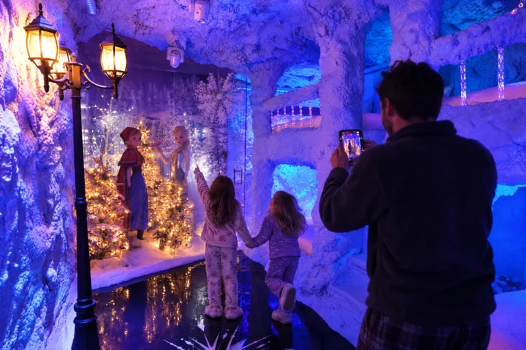 A dad films his daughters running to the ice princess statues in the snowy Ice Princess Suite at Electronic Ice Castle
