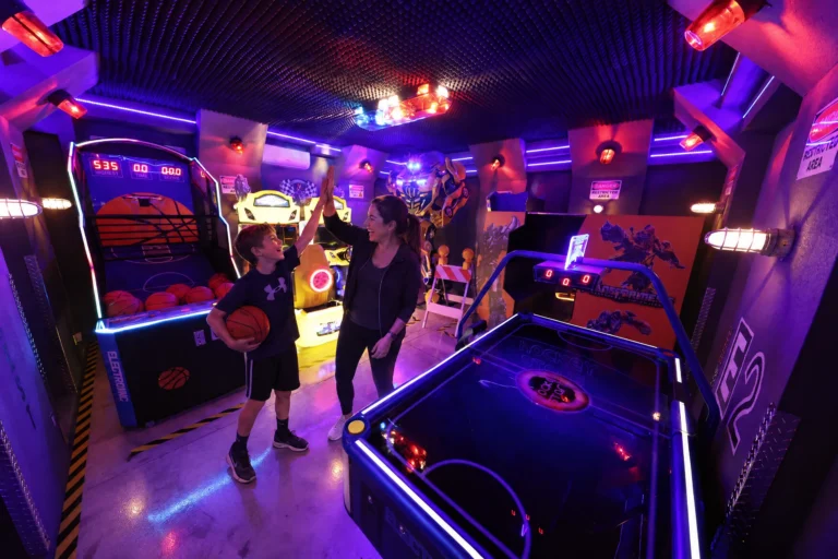 A mom and son high-five at the basketball game beside the neon air hockey table in the Robot Game Room at Electronic Ice Castle