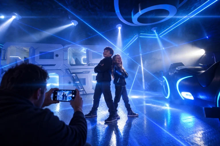A dad photographs his kids posing under the laser show in The Grid "The Secret Suite" at Electronic Ice Castle