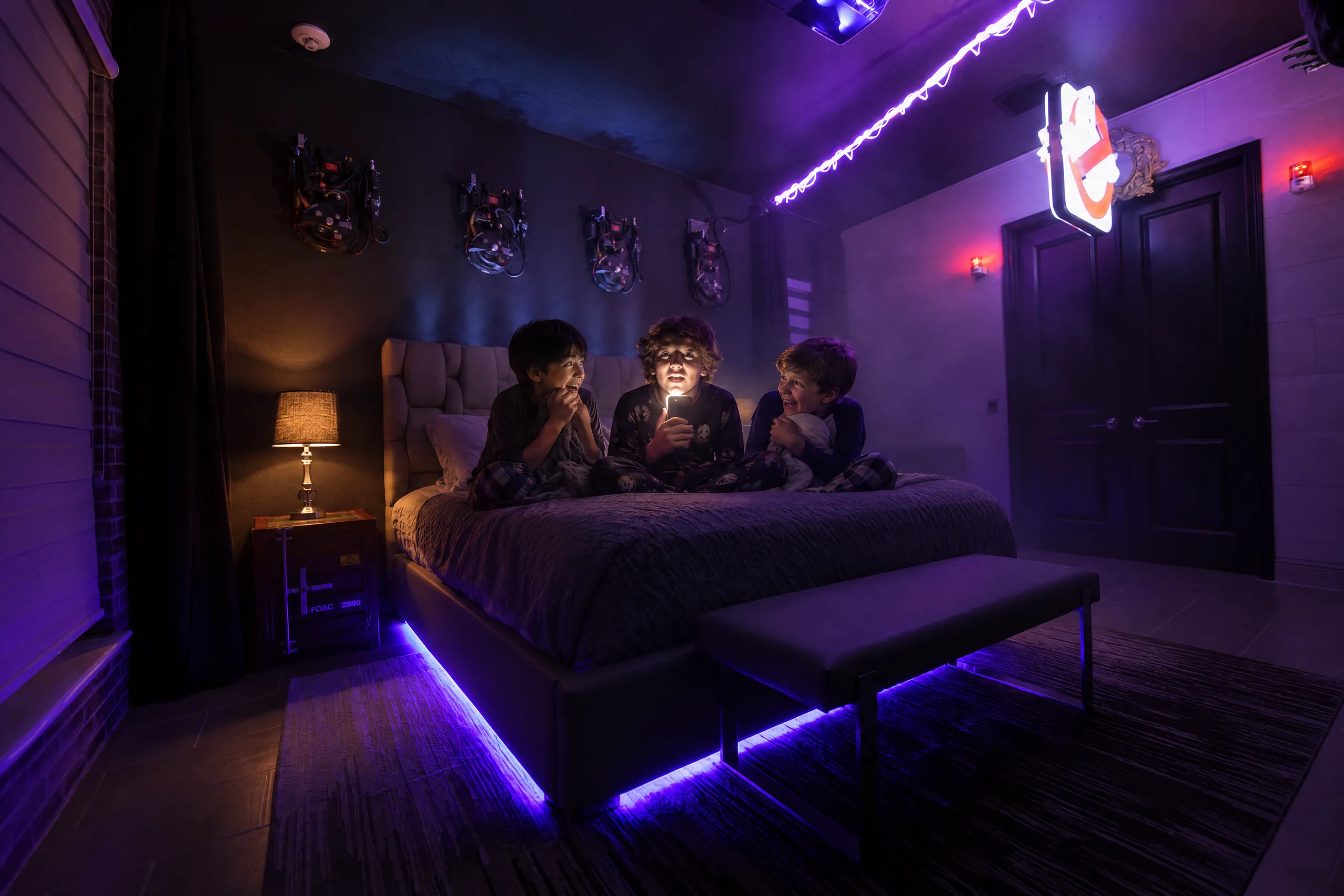 Cousins tell ghost stories by flashlight on the glowing bed in the Snoozebusters suite at The Electronic Ice Castle