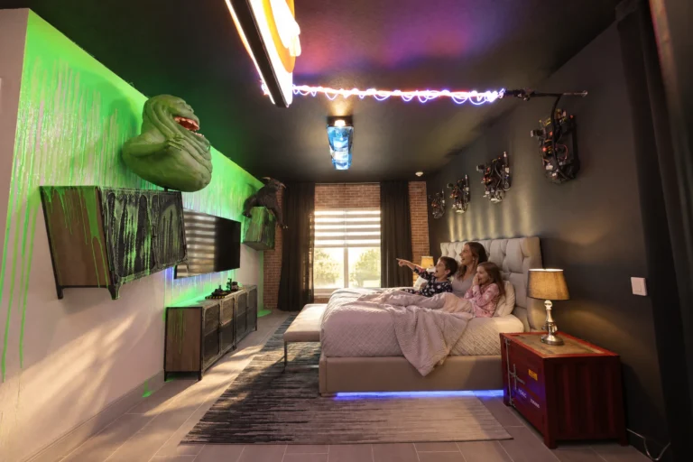 A family relaxes on the bed under neon lights in the Snoozebusters suite at Electronic Ice Castle
